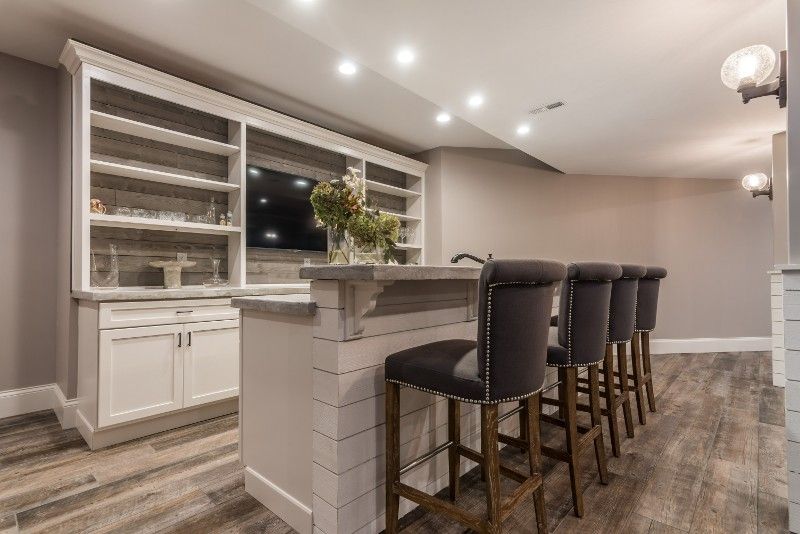 A basement with a bar and stools and a flat screen tv.