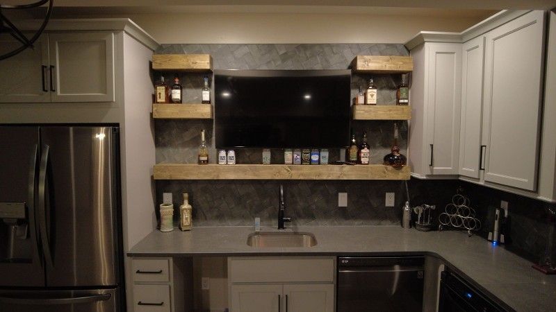 A kitchen with stainless steel appliances and a flat screen tv above the sink.