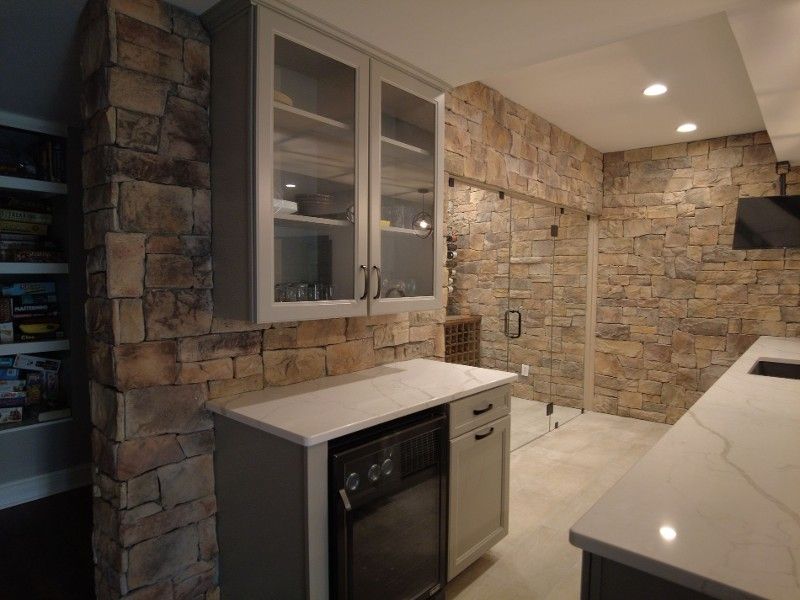 A kitchen with a stone wall and a refrigerator.