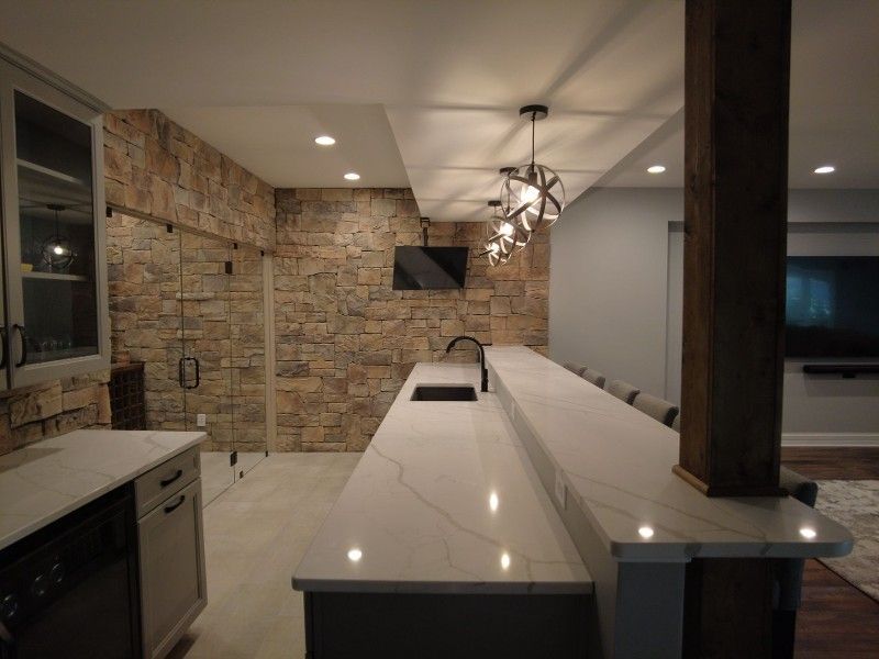 A kitchen with a long counter and a stone wall.