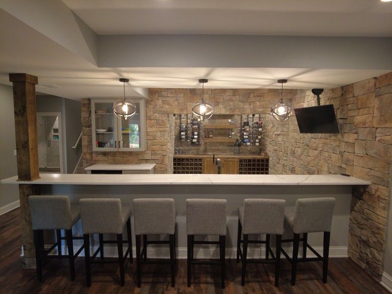 A basement bar with a long counter and stools.