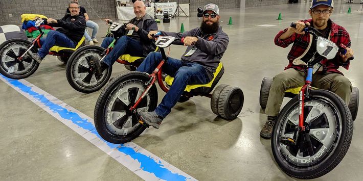 A group of men are riding go karts on a track.