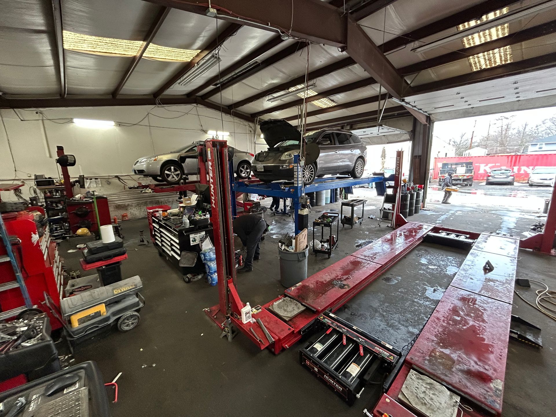 Auto repair shop with cars on lifts, tools, and a technician working.