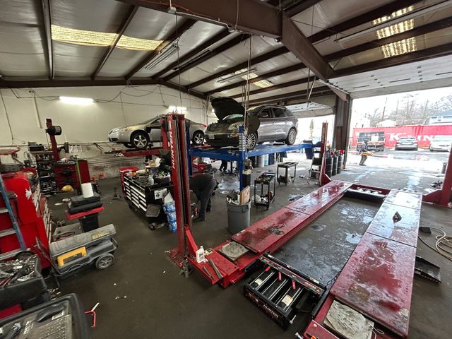 Auto repair shop with cars on lifts, tools, and a technician working.