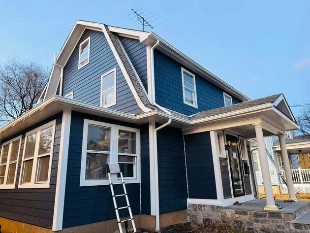 Blue two-story house with white trim and a ladder leaning against the front window