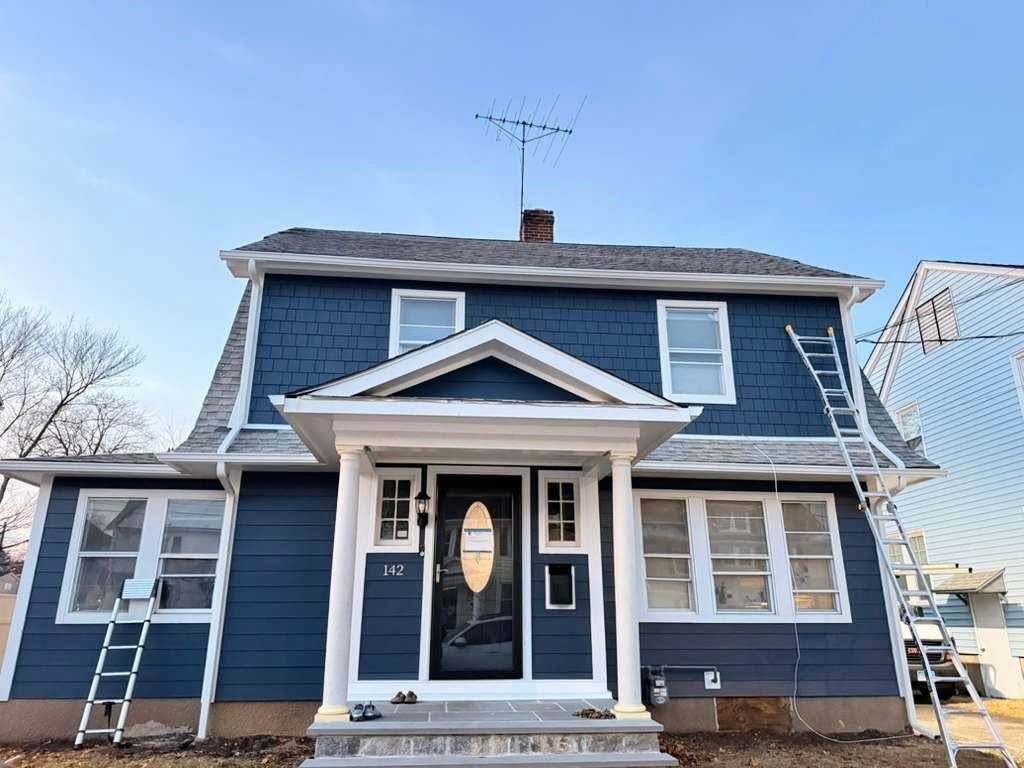 Blue two-story house with white trim and front porch, viewed from the street.