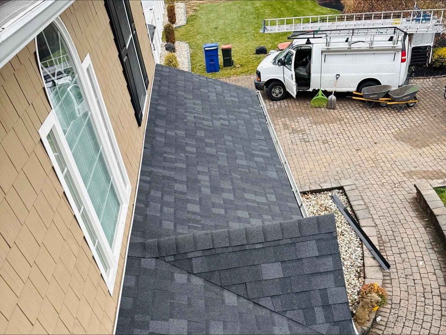 Roof repair on a house beside a white utility van in a driveway.