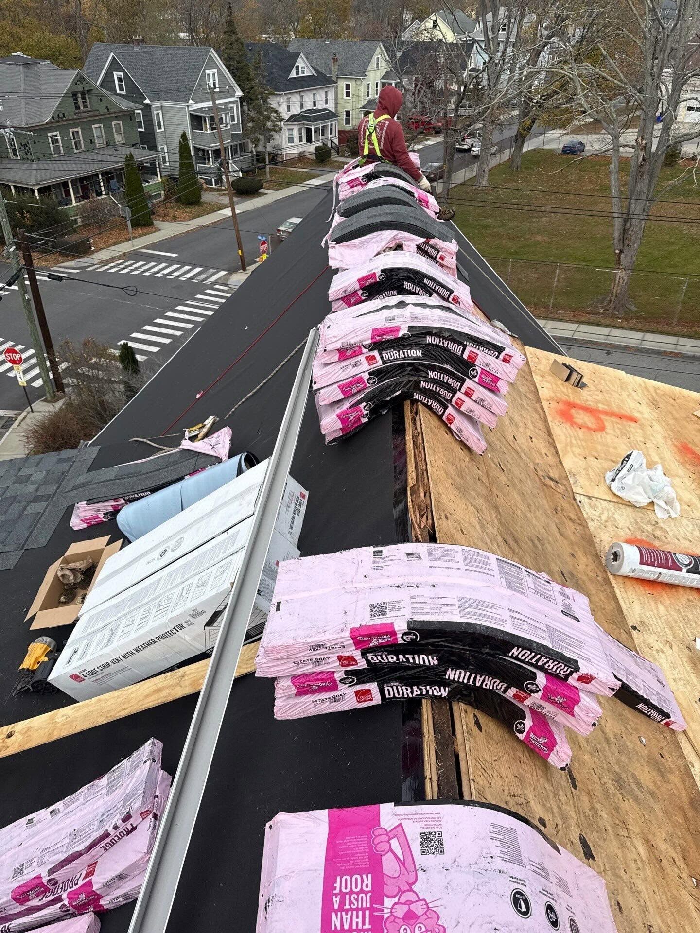 Shingled roof with pink roof vents and papers, viewed from above on a house under repair