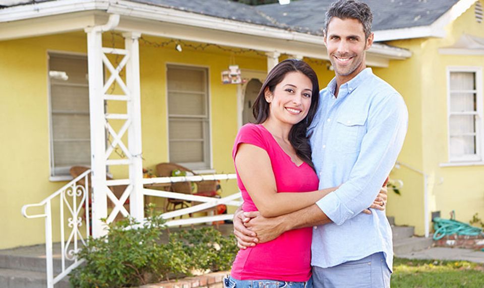 Couple Standing Outside Suburban Home