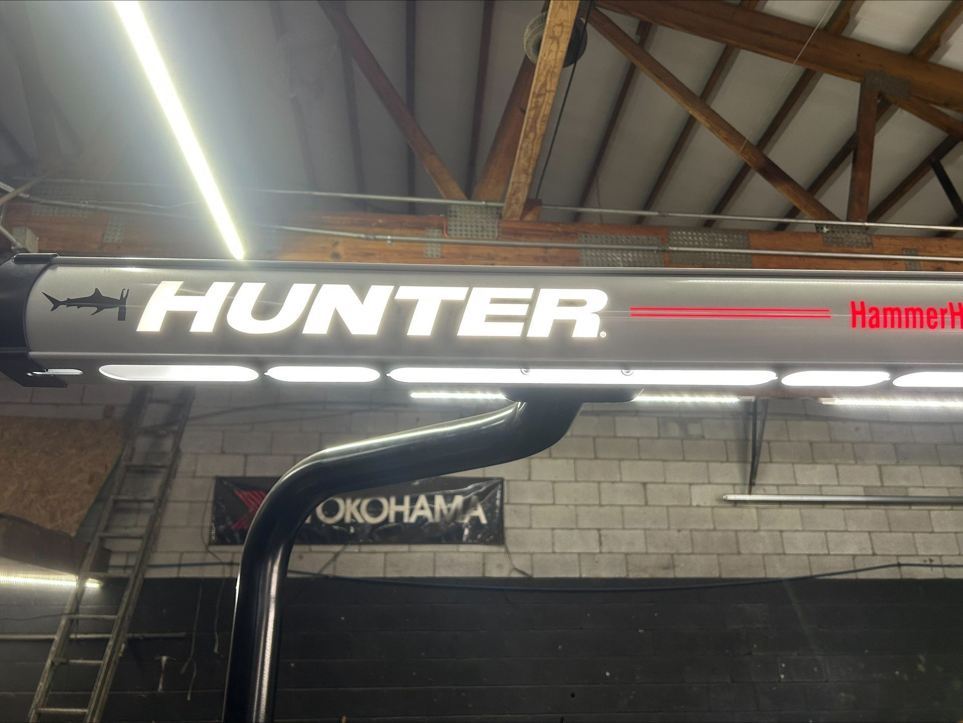 Hunter HammerHead alignment machine sign, gray and red, with a shark graphic, in a garage setting.