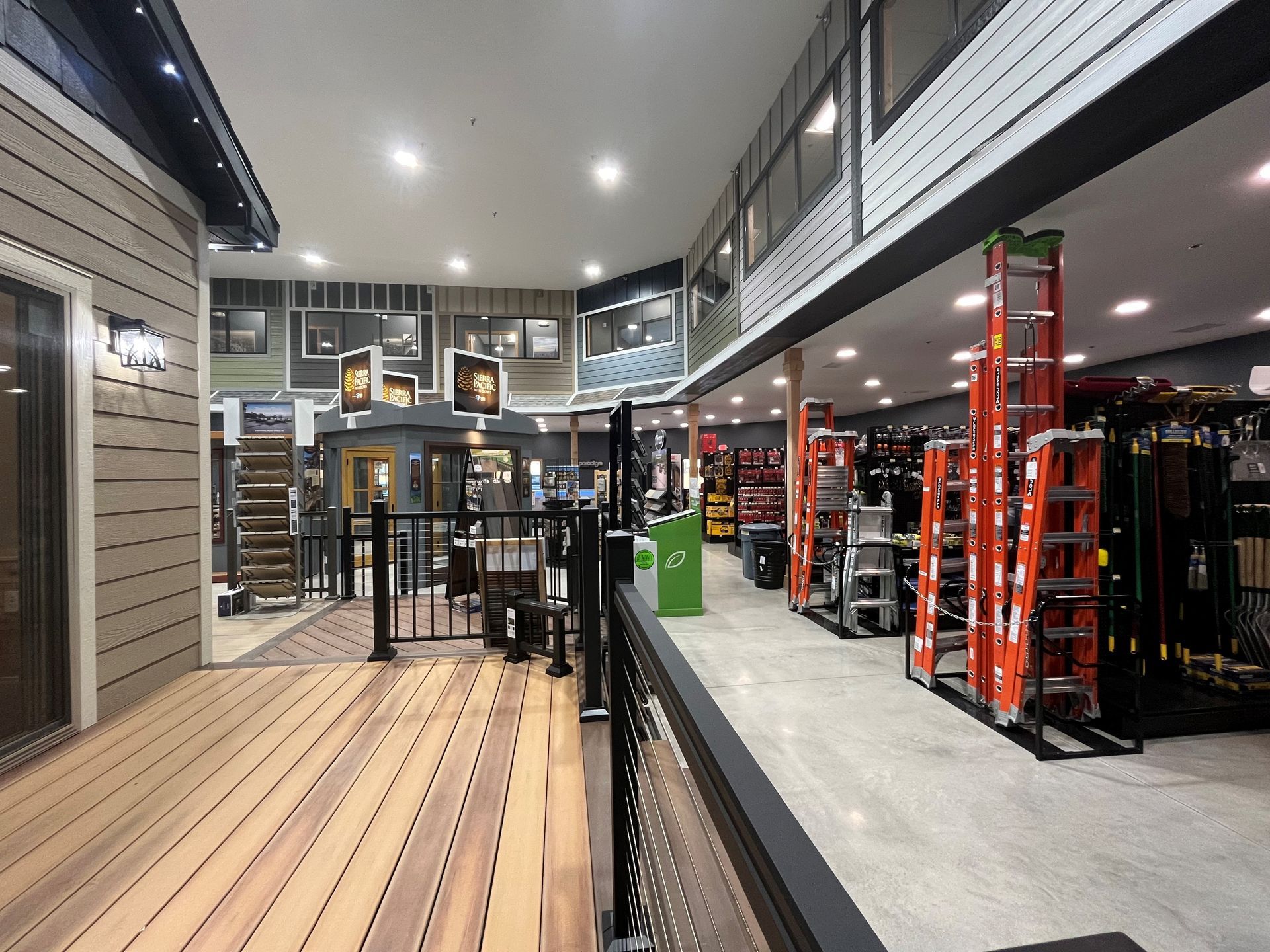 Interior of a building materials store with displays, a deck, and ladders.