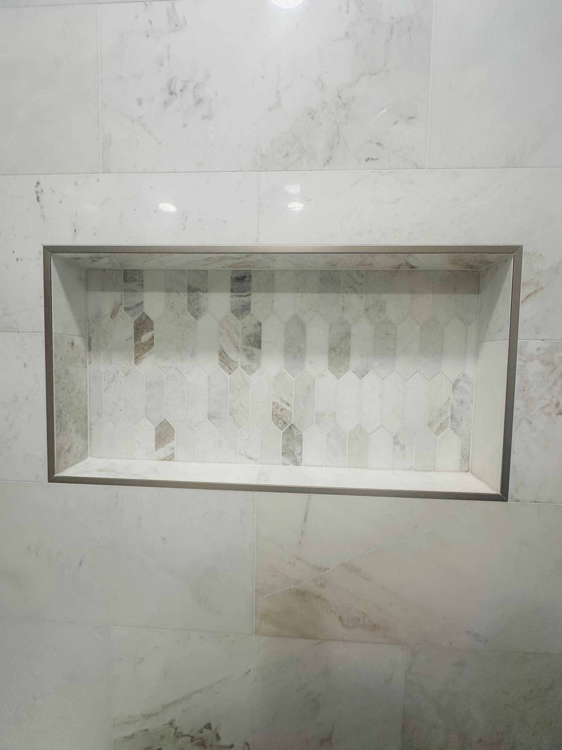 Small rectangular recessed wall niche with a white, worn interior and gray stone or tile surround.