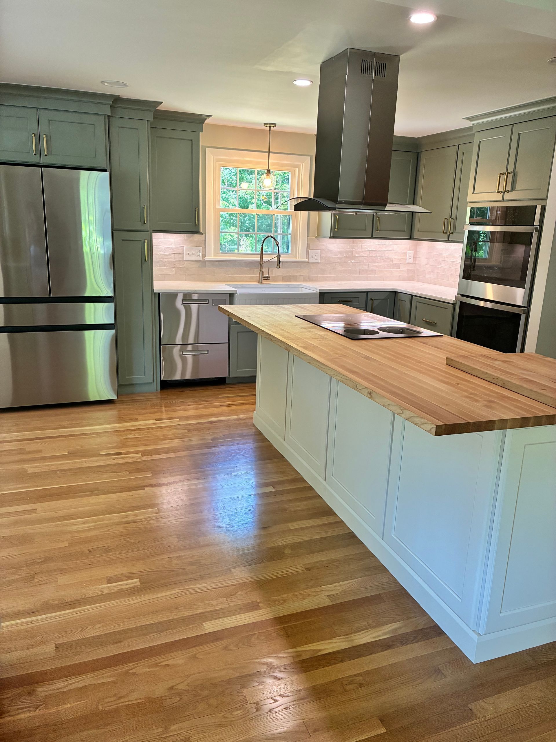Bright kitchen with stainless appliances, white cabinets, wood island, and hardwood floors