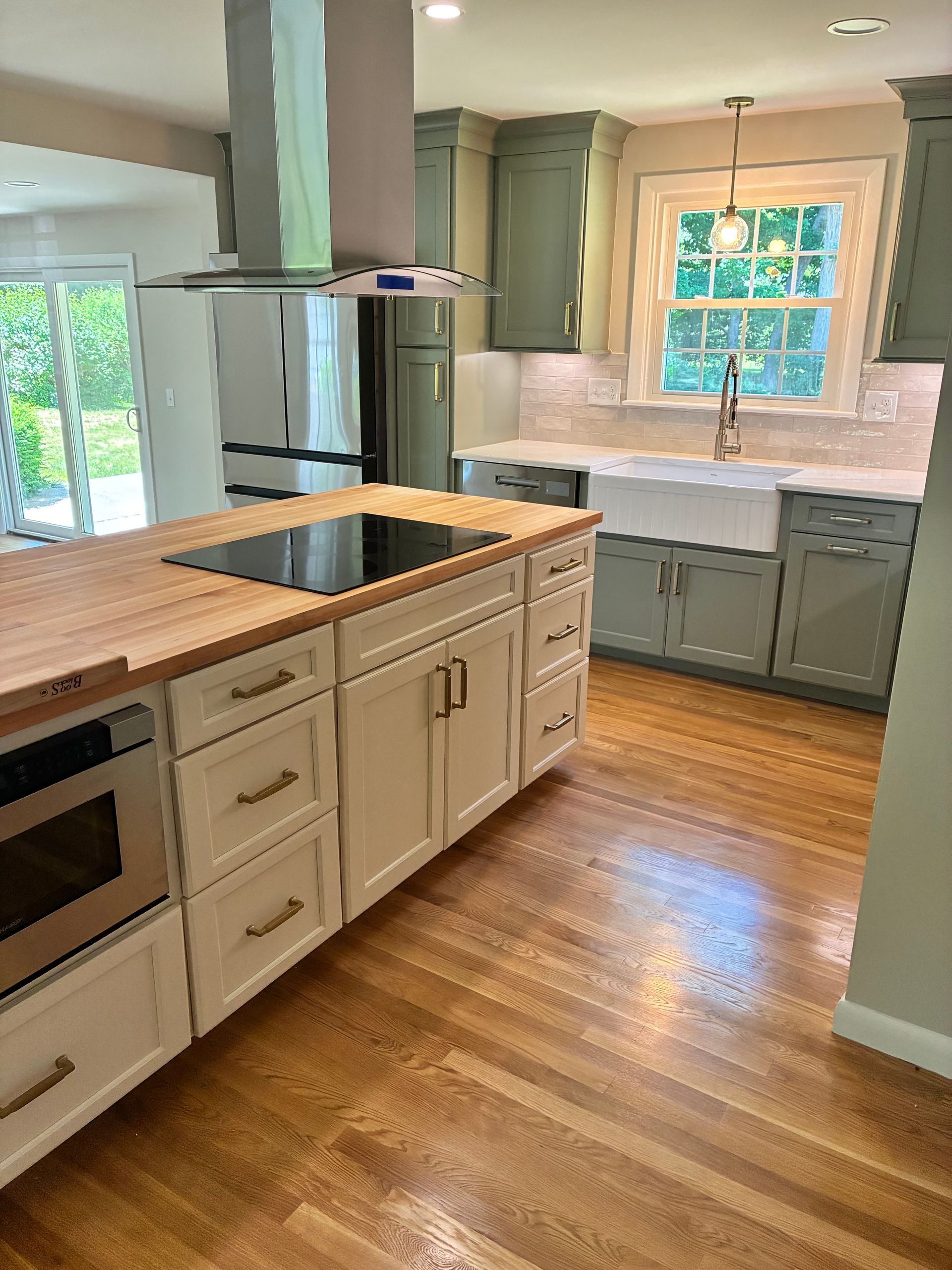 Bright kitchen with wood floors, central island, stainless fridge, and window over the sink.
