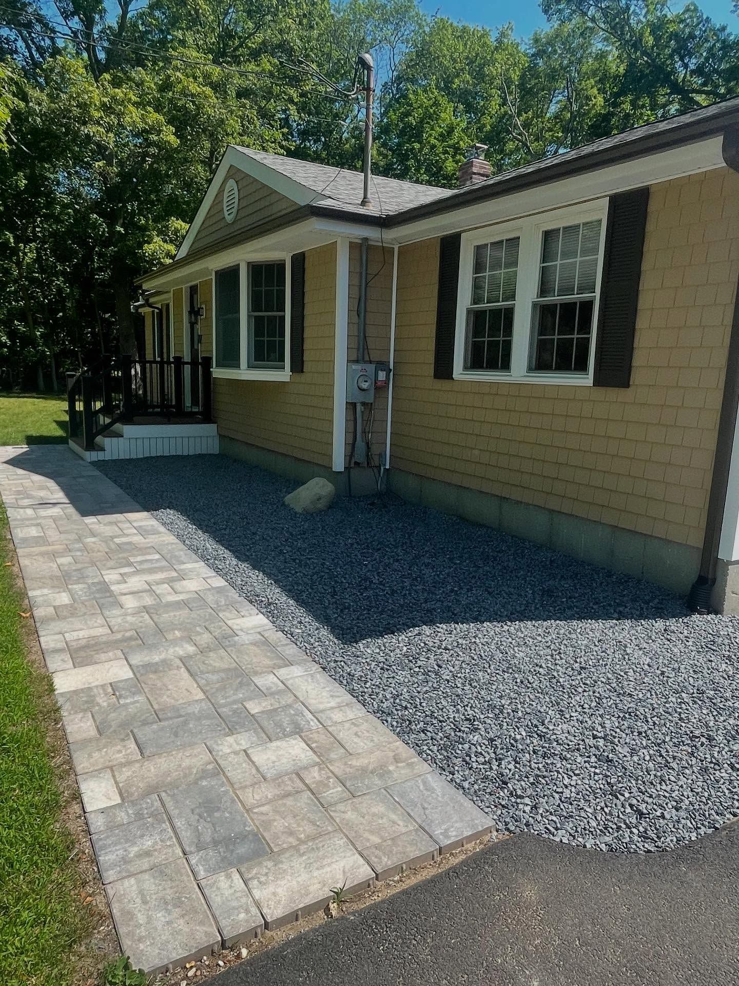 Tan ranch-style house with dark door, small porch, and yard; cloudy sky above.