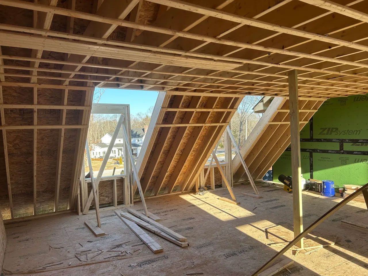 Interior view of a building under construction. Wooden framing for walls and ceiling, with visible windows.