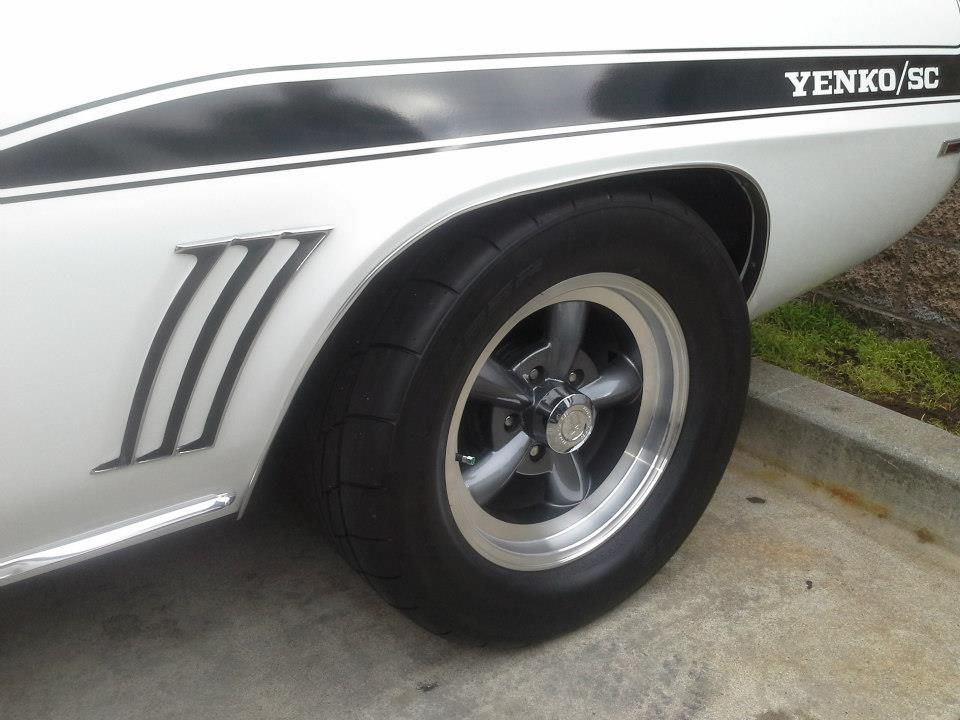 Close-up of a white Yenko/SC muscle car rear quarter panel featuring signature side stripes and chrome five-spoke wheels.