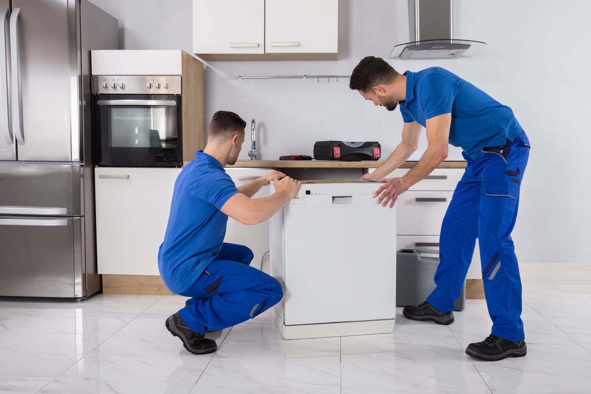 Two technicians installing a dishwasher in a kitchen.
