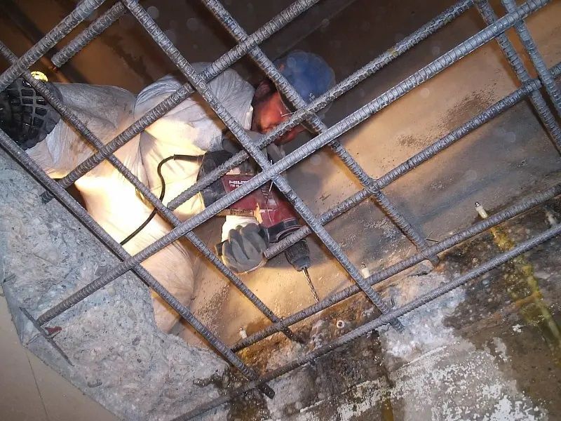 A man is working on a concrete wall with a drill