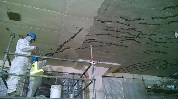 A group of construction workers are working on a ceiling.