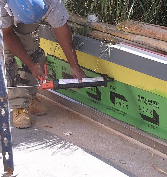 A man wearing a blue hard hat is working on a green and yellow wall