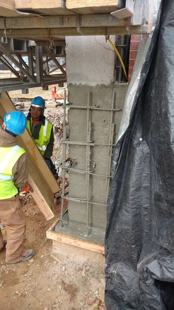 A group of construction workers are working on a concrete column.