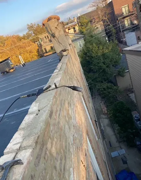 Brick wall on rooftop, showing visible damage and tools.