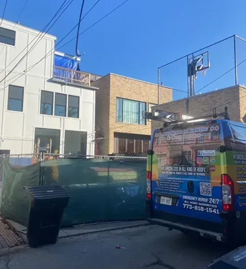 Buildings under construction with a construction van parked in front. Blue sky.