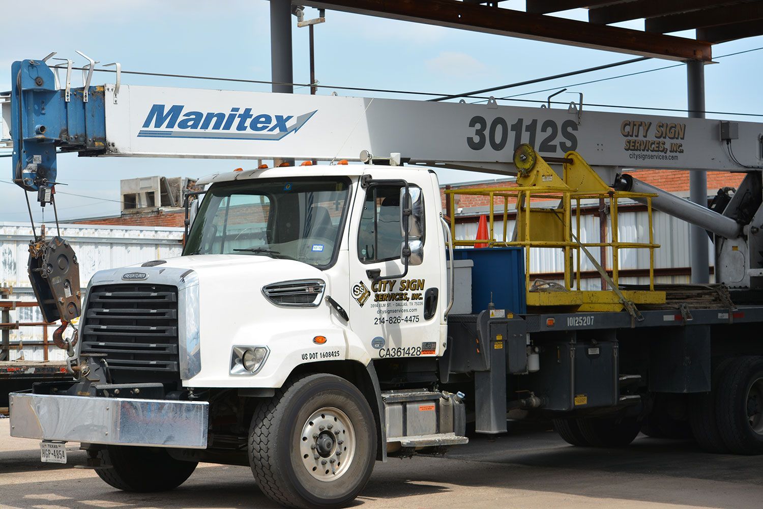 A white truck with a crane attached to it is parked in a parking lot