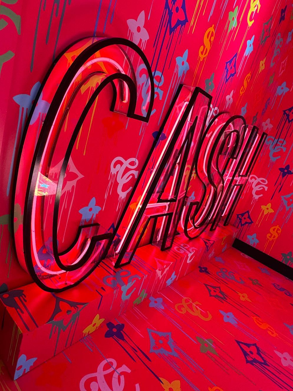 A neon sign that says cash on a pink background