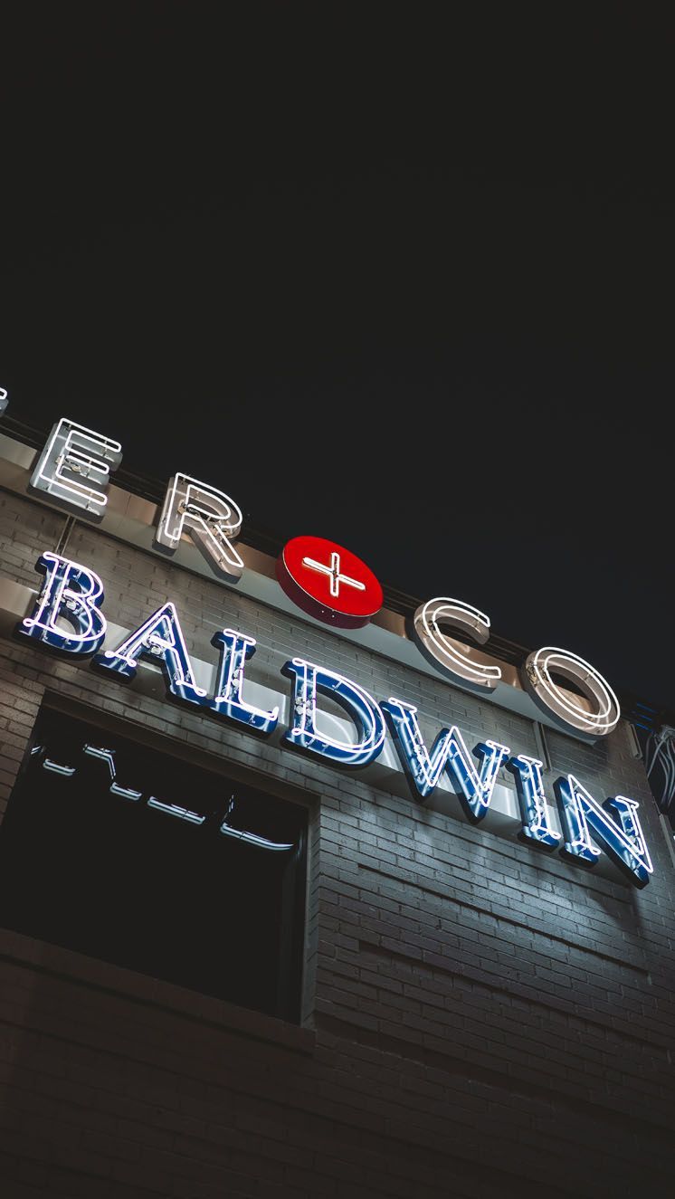 A Baldwin sign is lit up at night on the side of a building