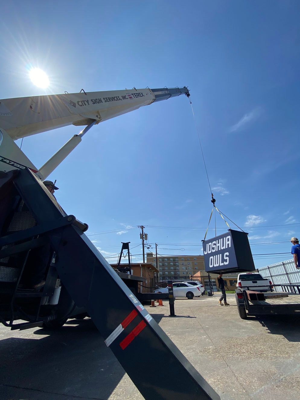 A crane is lifting a sign that says los huf dallas