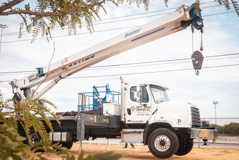 A white truck with a crane attached to it is parked on the side of the road