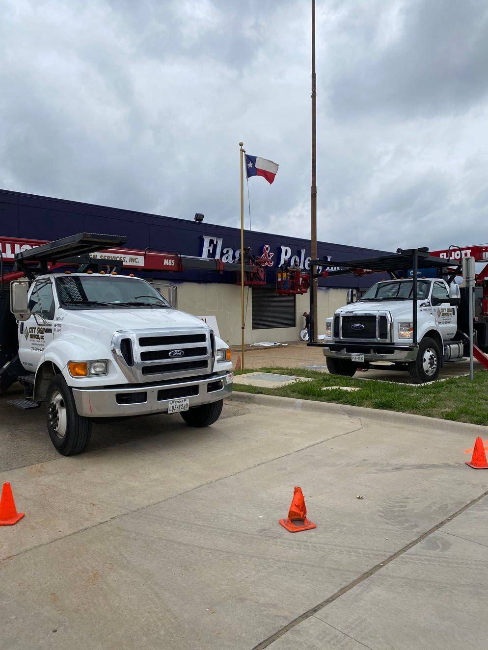 Two white trucks are parked in front of a building