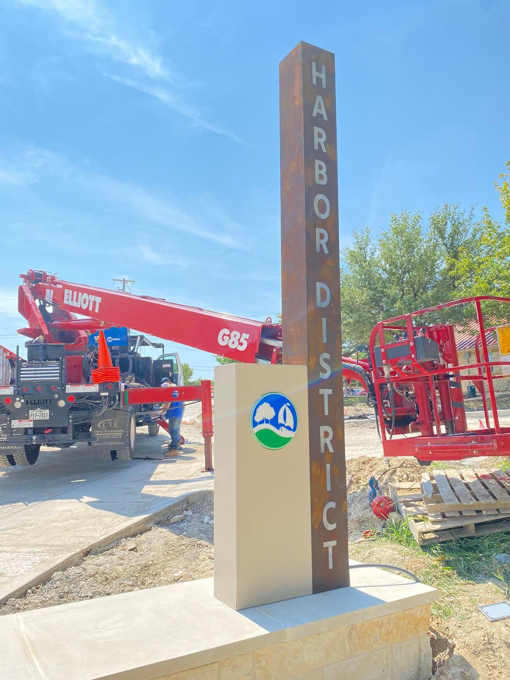 A large red crane is parked in front of a sign that says Harbor District