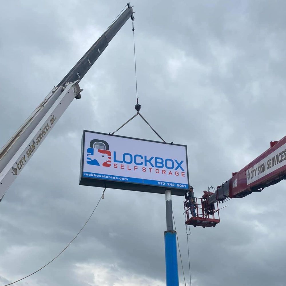 A sign for lockbox self storage is being lifted by a crane