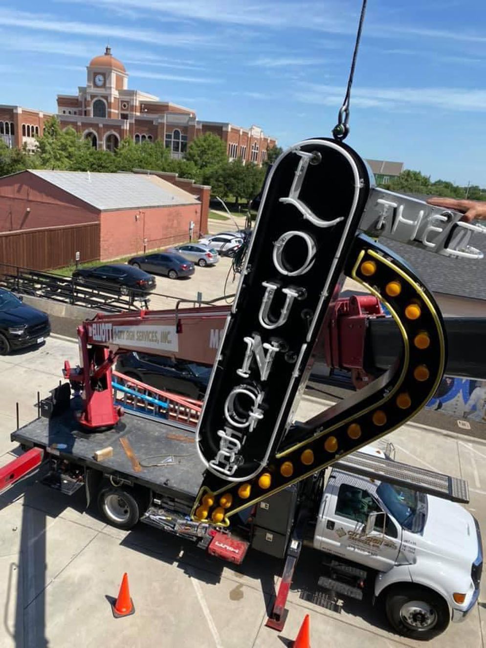 A large lounge sign is being lifted by a crane