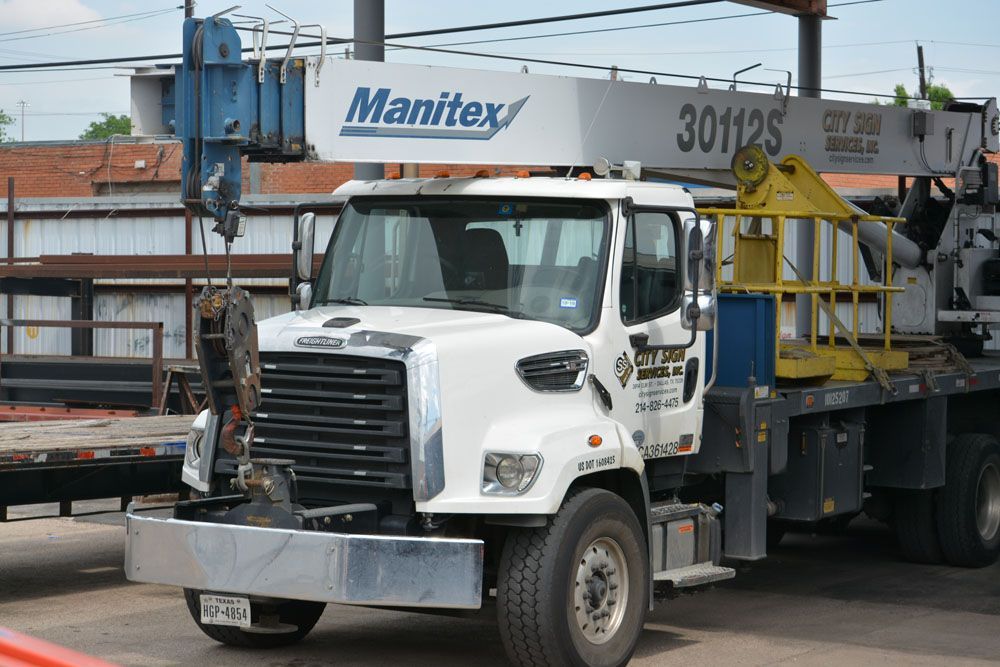 A white manitex truck is parked in a parking lot