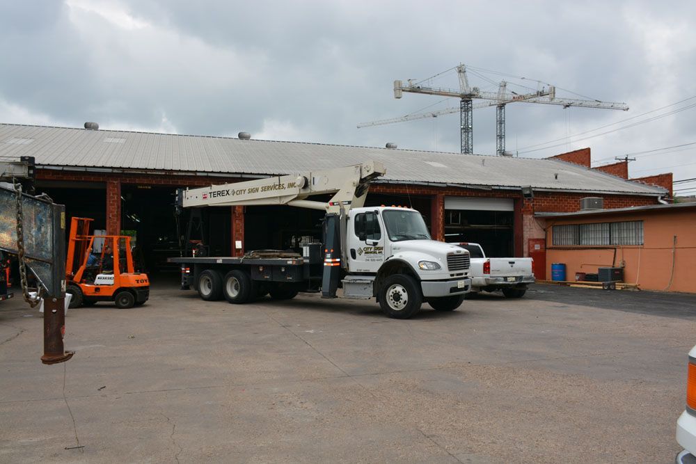 A white truck with a crane on top is parked in front of a building