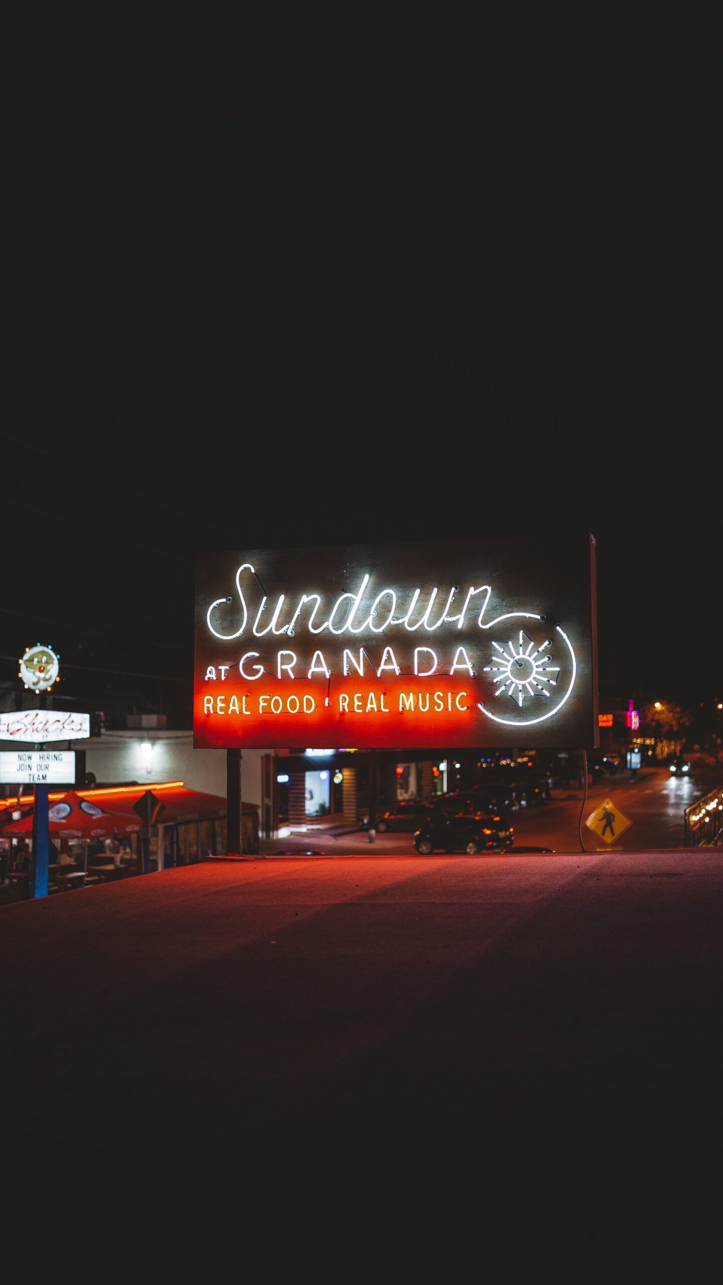 A neon sign for sundown granada is lit up at night
