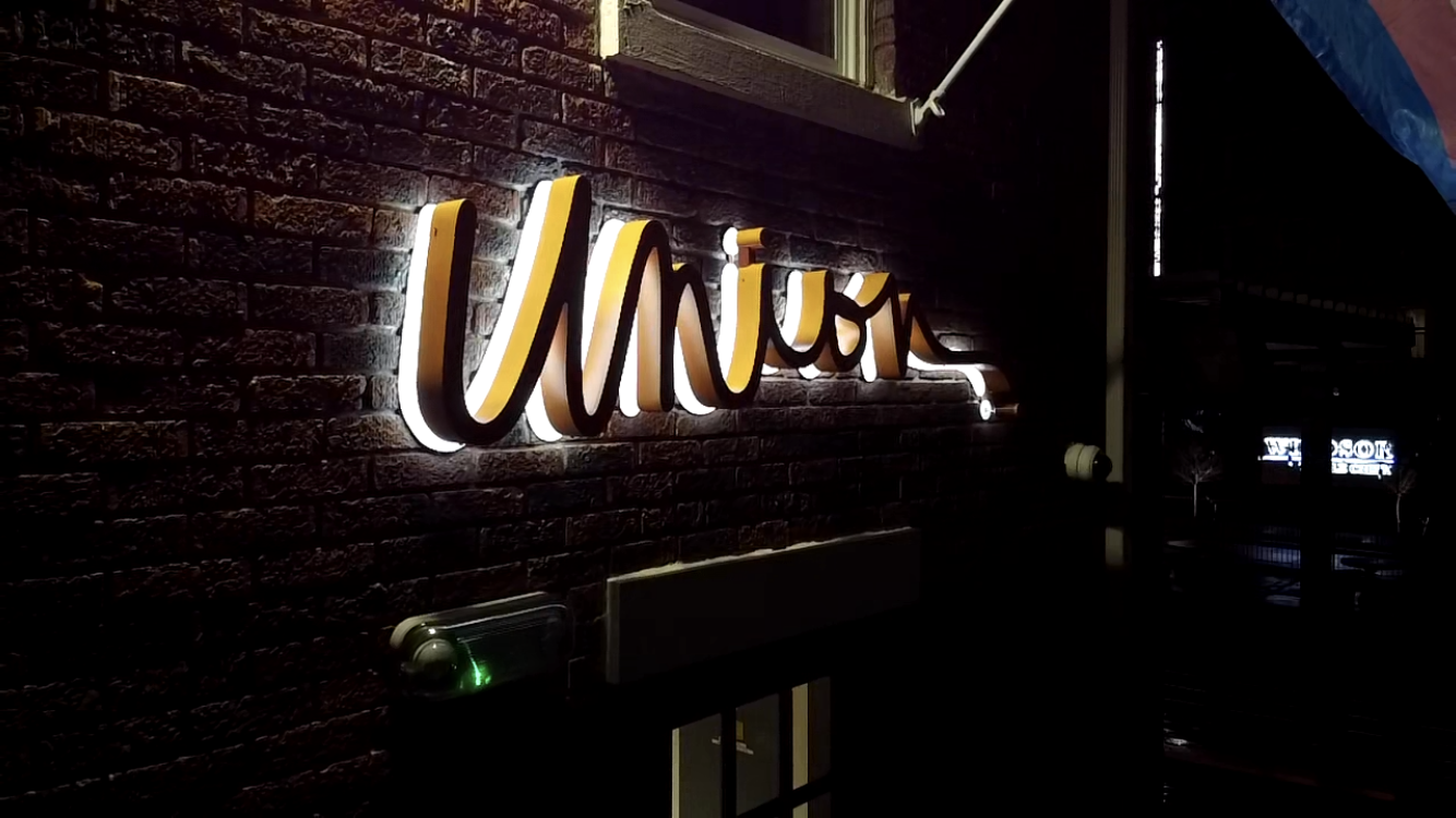 The word union is lit up on a brick wall at night.