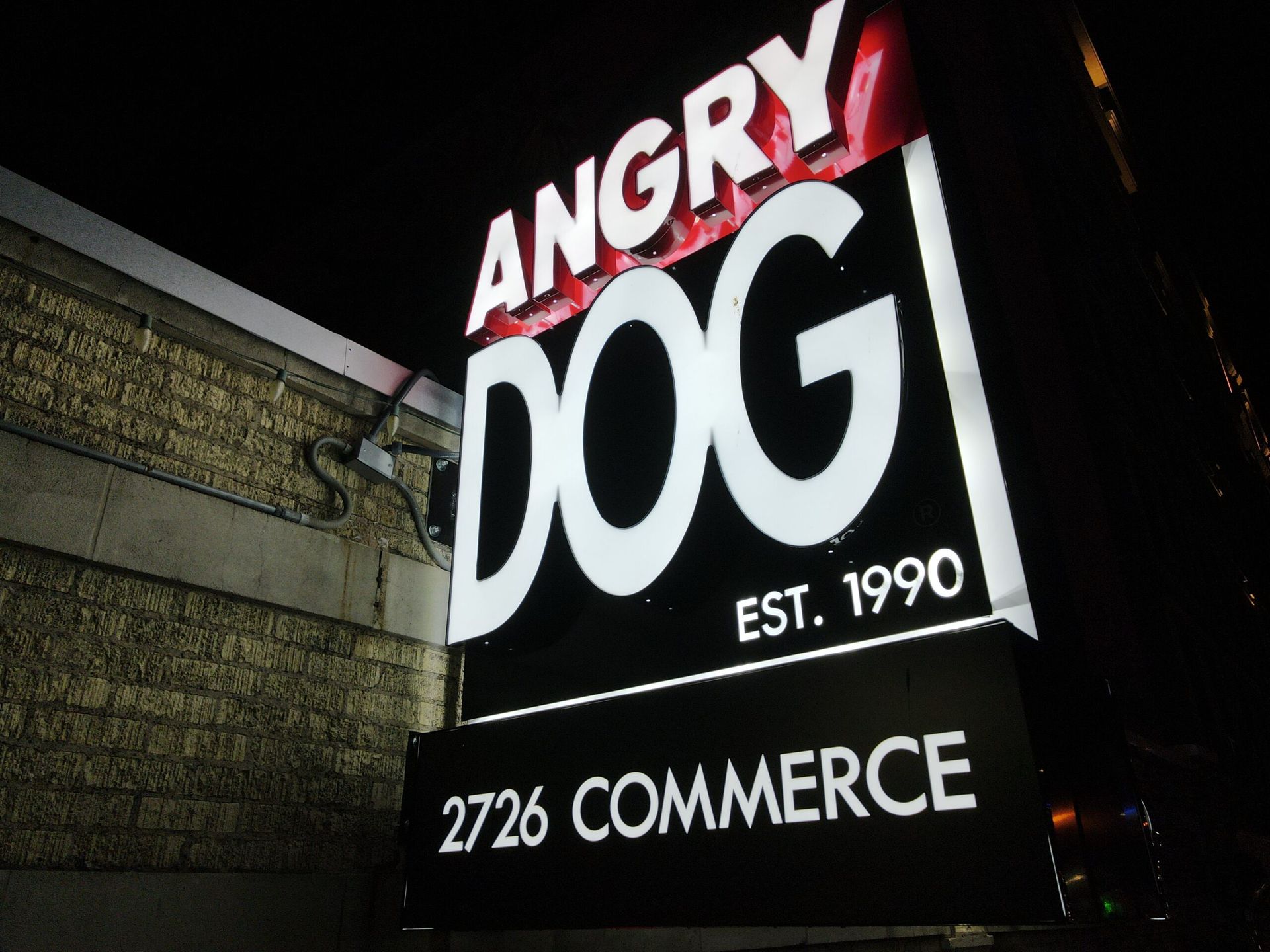 A sign for angry dog is lit up at night