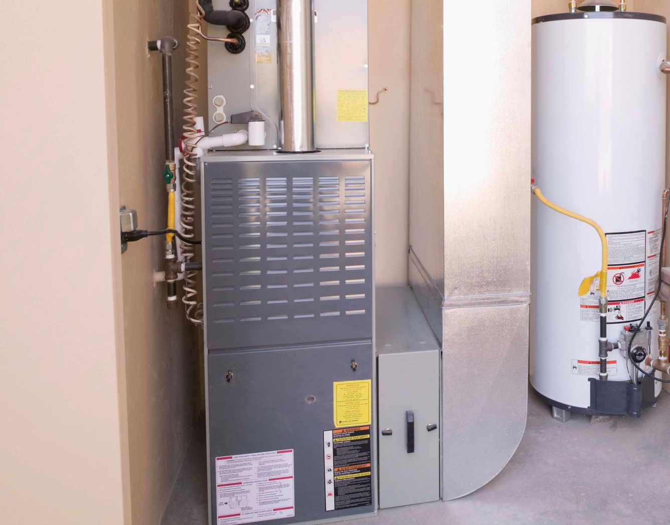Furnace and water heater in a utility closet; gray and white appliances in a beige room.