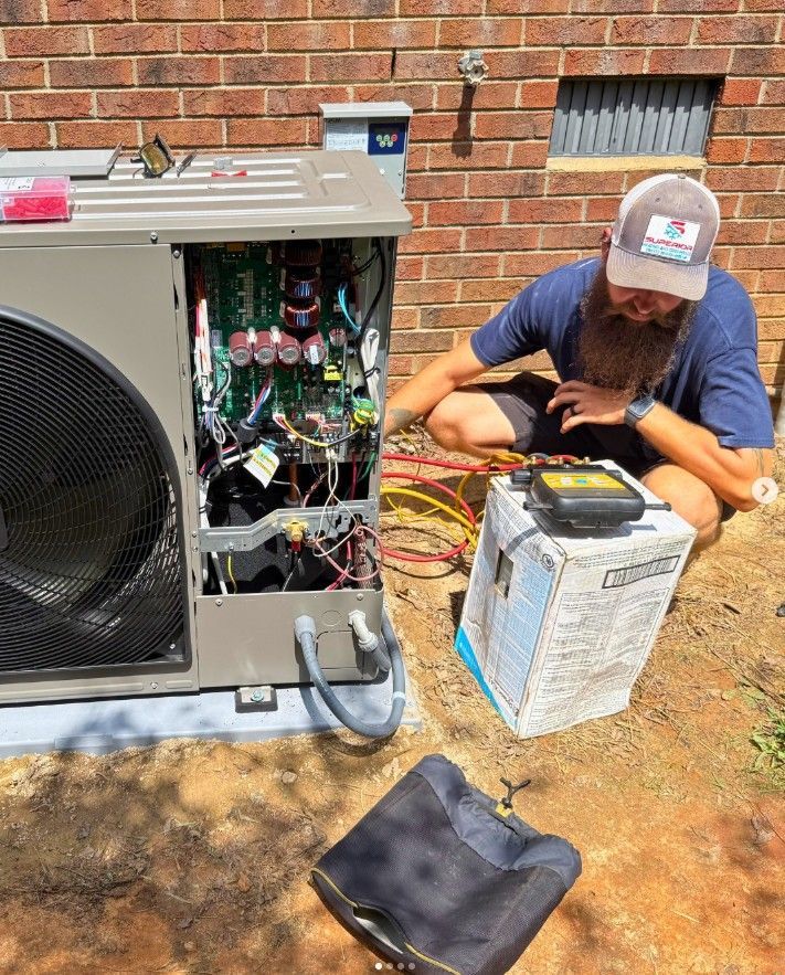 A man working on an air conditioning unit outside, inspecting its inner components.
