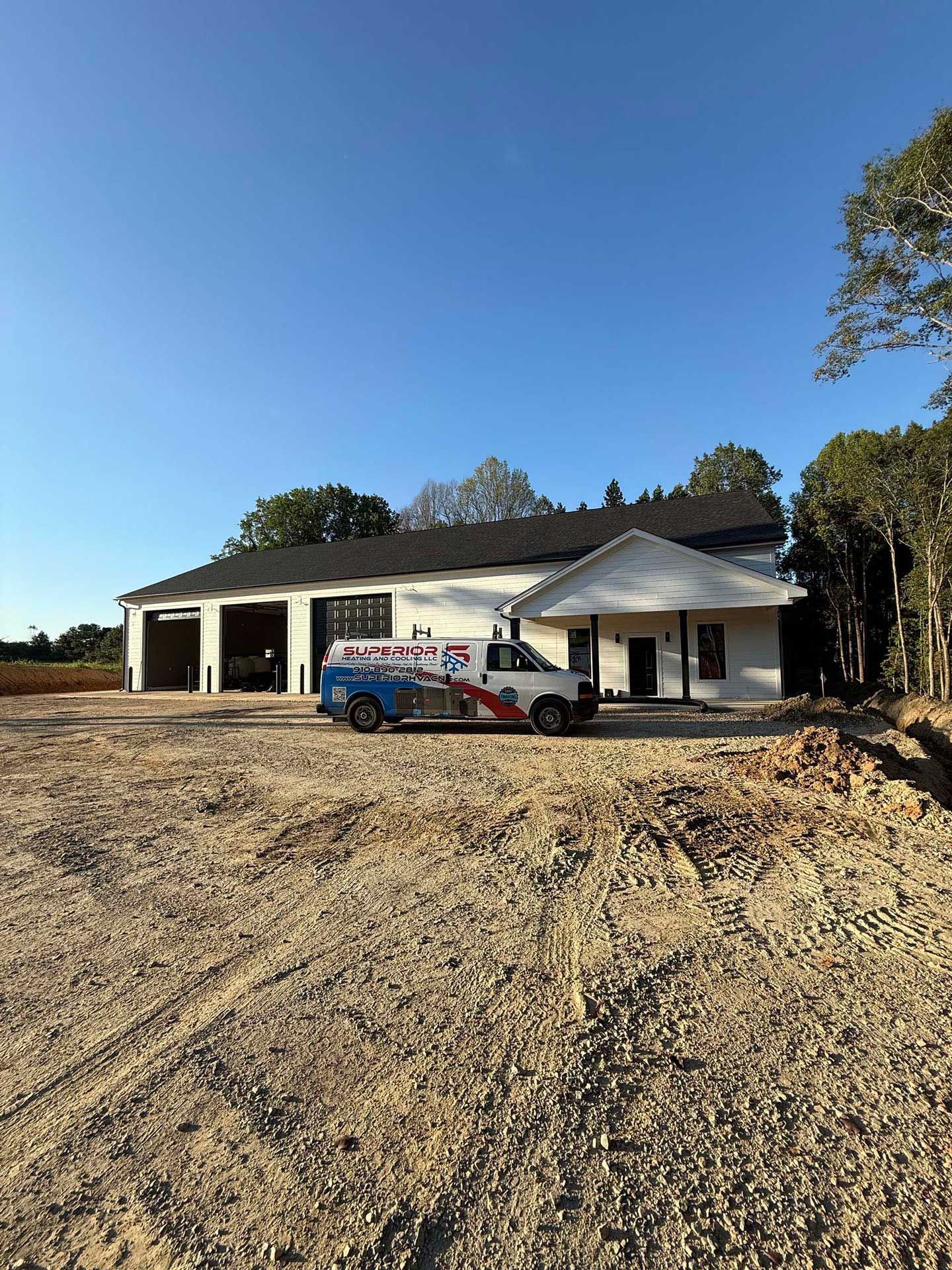 White building with garage doors, HVAC truck parked in front.