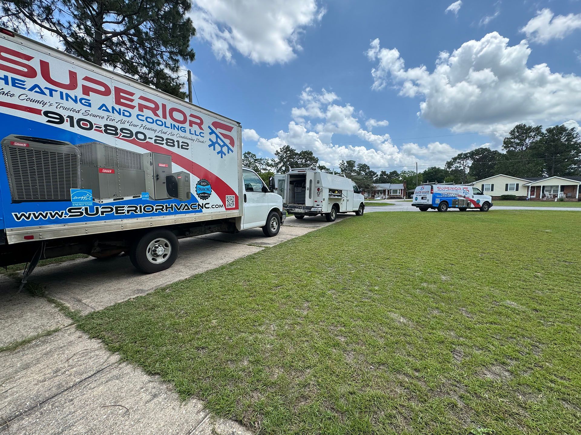 Three HVAC service trucks parked on a lawn, one labeled 