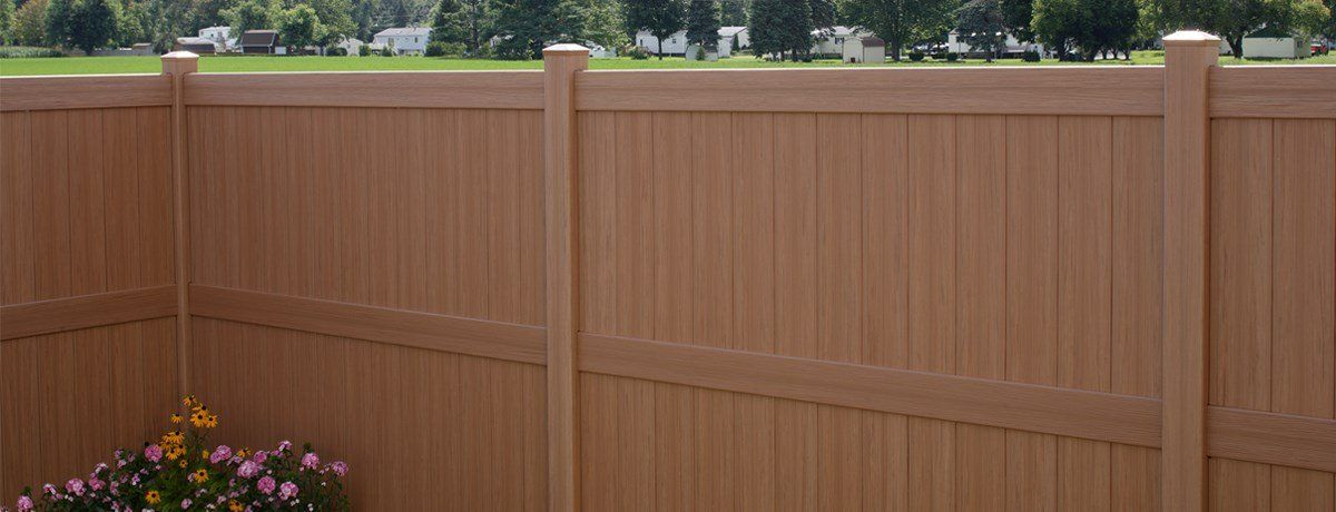 A wooden fence with flowers in front of it