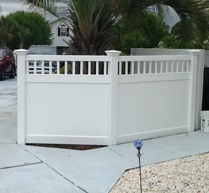 A white fence with a palm tree in the background