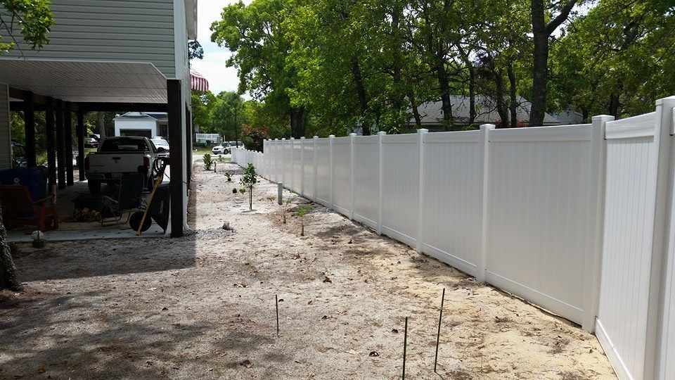 A white fence is being built in the backyard of a house.