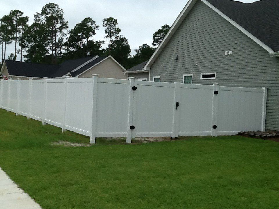 A white fence with a gate in front of a house